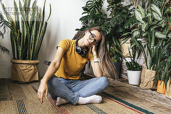 Porträt einer entspannten jungen Frau  die zu Hause auf dem Boden sitzt