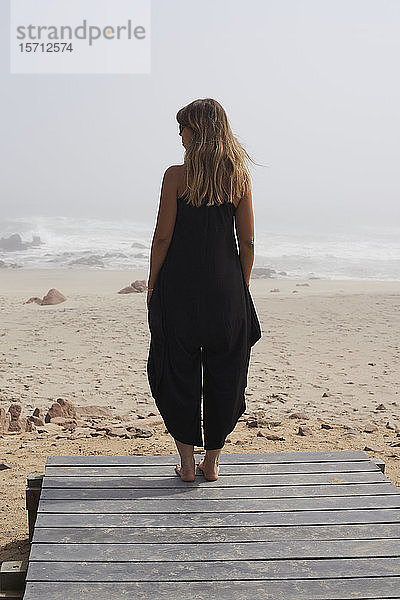 Rückansicht einer am Meer stehenden Frau  Kreuz am Kap  Namibia