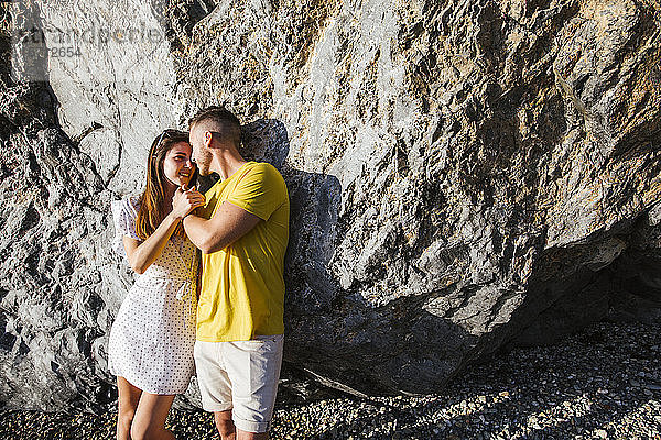 Junges Paar  das sich auf einen Felsen lehnt und Händchen hält