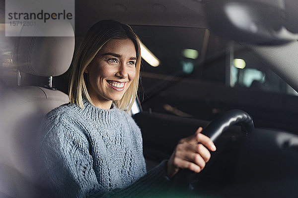 Porträt einer glücklichen jungen Frau am Steuer eines Autos