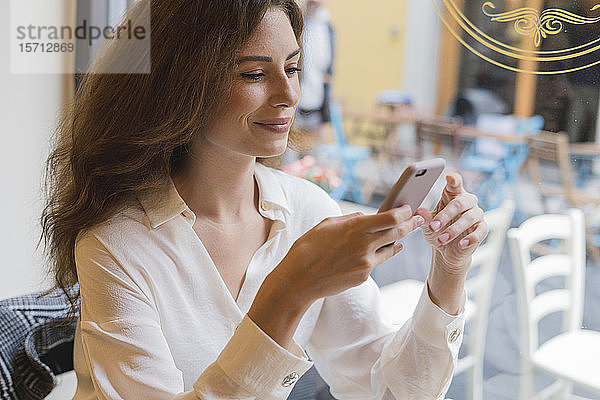 Porträt einer jungen Frau mit Handy in der Hand in einem Cafe