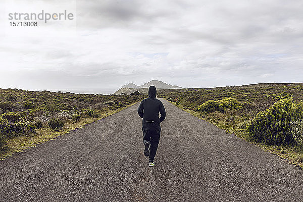 Rückenansicht eines auf der Landstraße joggenden Mannes  Cape Point  Westkap  Südafrika