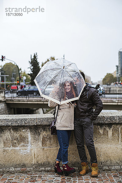 Verliebtes Paar mit durchsichtigem Regenschirm im Herbst