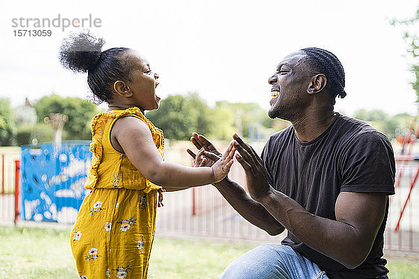 Glückliche Vater und Tochter beim Klatschspiel in einem Park