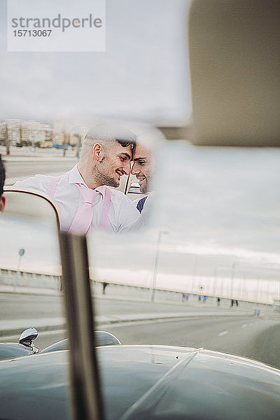 Spiegelung im Rückspiegel eines eleganten schwulen Paares in einem Oldtimer-Cabriolet