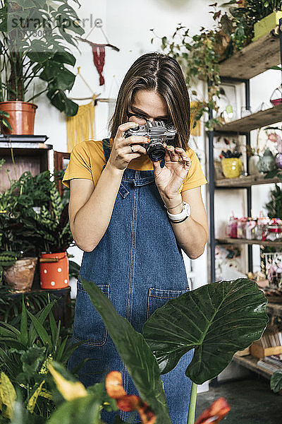 Junge Frau beim Fotografieren von Pflanzen in einem kleinen Gartenbaubetrieb
