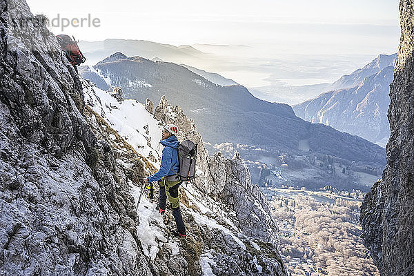 Alpinist steht in einem felsigen  schneebedeckten Berg und schaut nach oben  Orobie Alps  Lecco  Italien