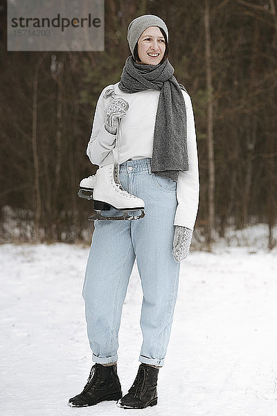 Porträt einer lächelnden Frau mit Schlittschuhen im Winter