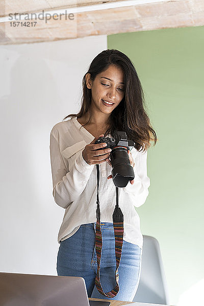 Porträt eines lächelnden jungen Architekten mit Kamera und Laptop in einem Atelier
