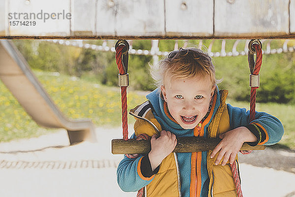 Porträt eines blonden kleinen Jungen auf einem Spielplatz