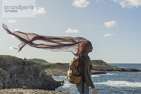 Junge Frau an der Küste mit Tuch um das Gesicht  Ibiza  Spanien