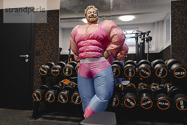 Stolzer Mann in rosa Bodybuilder-Kostüm in Turnhalle