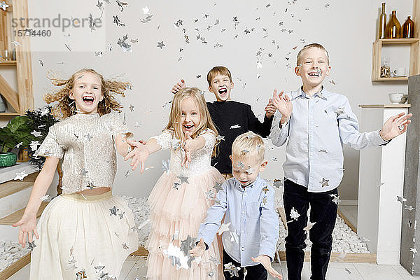 Gruppenbild von fünf Kindern  die sich mit Weihnachtskonfetti vergnügen
