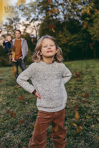 Porträt eines selbstbewussten Mädchens mit ihrer Familie auf einer Wiese im Herbst