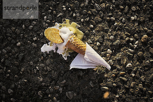 Verlorene Eiswaffel auf Asphalt in der Abenddämmerung