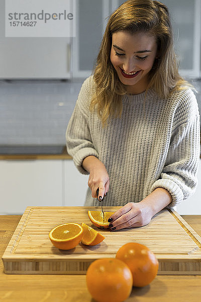 Weiblicher Teenager beim Orangenschneiden in der Küche