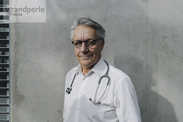 Porträt eines selbstbewussten Oberarztes an einer Betonwand