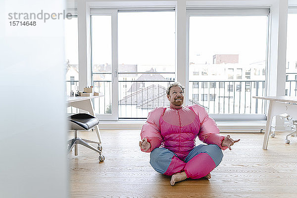 Geschäftsmann im Büro in rosa Bodybuilder-Kostüm  der Yoga praktiziert