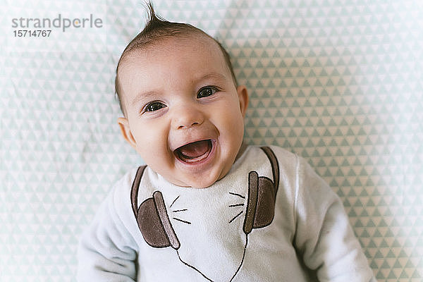 Porträt eines lachenden Mädchens mit applizierten Kopfhörern auf einem Pyjama