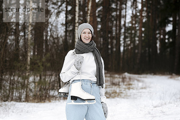 Porträt einer glücklichen Frau mit Schlittschuhen im Winter