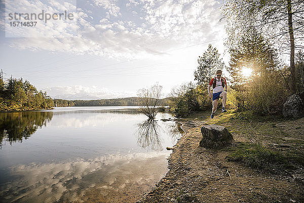 Mann läuft bei Sonnenuntergang am See  Forstsee  Kärnten  Österreich