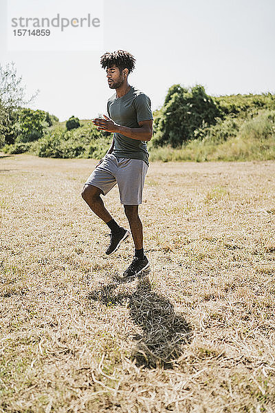 Junger Mann während des Trainings joggt auf der Stelle in einem Park