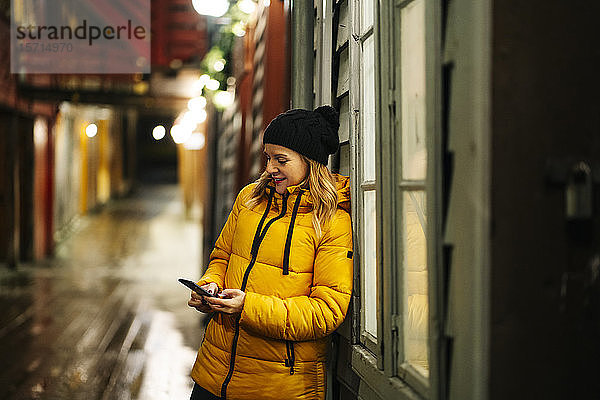 Frau trägt eine gelbe Jacke und benutzt ein Smartphone in Bergen  Norwegen