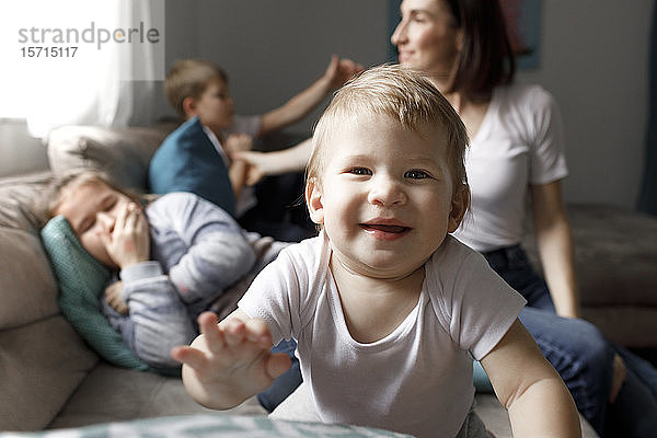 Porträt eines glücklichen kleinen Jungen mit seiner Familie auf der Couch im heimischen Wohnzimmer