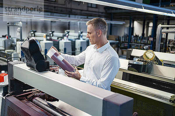 Mann in weißem Hemd in einer Fabrik untersucht Produkt