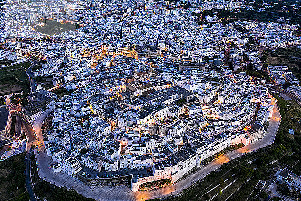 Italien  Provinz Brindisi  Ostuni  Luftaufnahme der Altstadtzitadelle umgeben von weißen Häusern in der Abenddämmerung