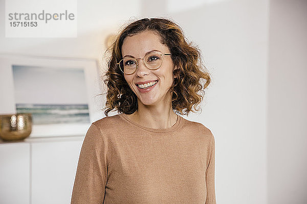 Porträt einer lächelnden brünetten Frau mit Brille zu Hause