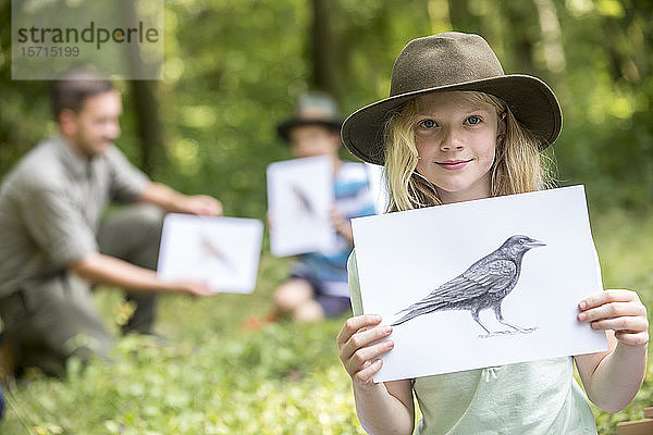 Schulkinder lernen etwas über Tierarten  Mädchen hält Bild eines Vogels
