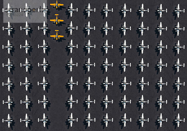 Luftbild von drei orangefarbenen Flugzeugen  umgeben von ausschließlich weißen Flugzeugen