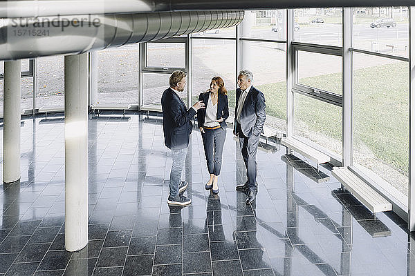 Geschäftsleute sprechen am Fenster in einem modernen Bürogebäude