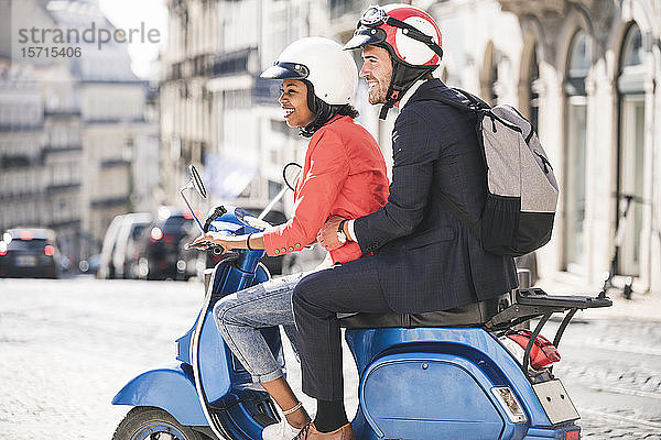 Glückliches junges Geschäftspaar fährt Motorroller in der Stadt  Lissabon  Portugal