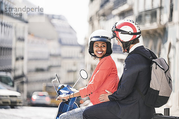 Glückliches junges Geschäftspaar auf einem Motorroller in der Stadt  Lissabon  Portugal