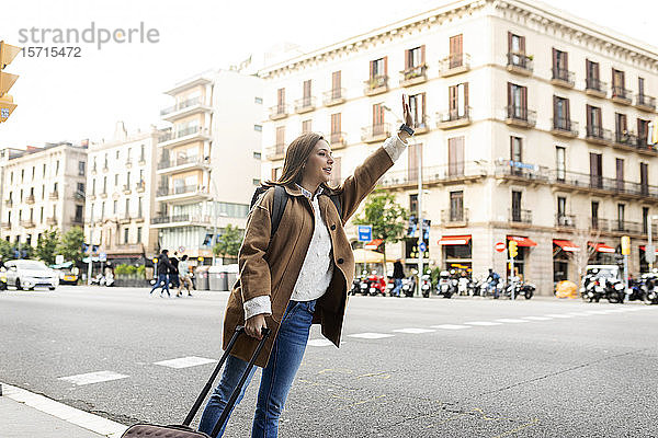 Junge Frau in der Stadt  die ein Taxi ruft  Barcelona  Spanien