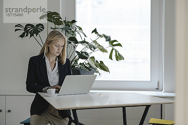 Junge Geschäftsfrau benutzt Laptop im Büro