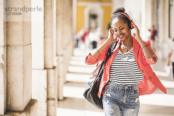 Glückliche junge Frau mit Kopfhörern beim Musikhören in der Stadt  Lissabon  Portugal