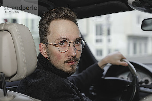 Porträt eines jungen Autofahrers mit Brille