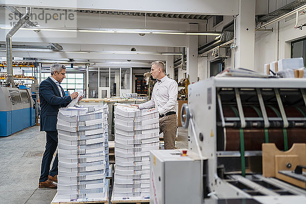 Zwei Geschäftsleute beim Papierstapel in einer Fabrik