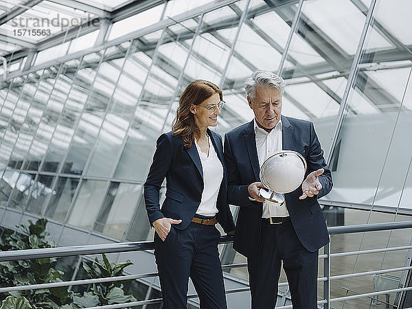 Geschäftsmann und Geschäftsfrau betrachten Globus in modernem Bürogebäude