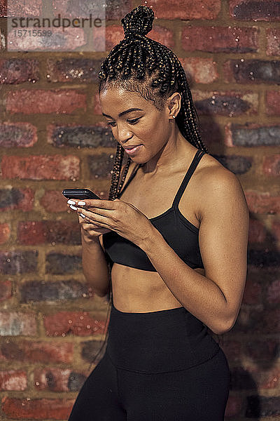 Weibliche Sportlerin benutzt Smartphone nach dem Training