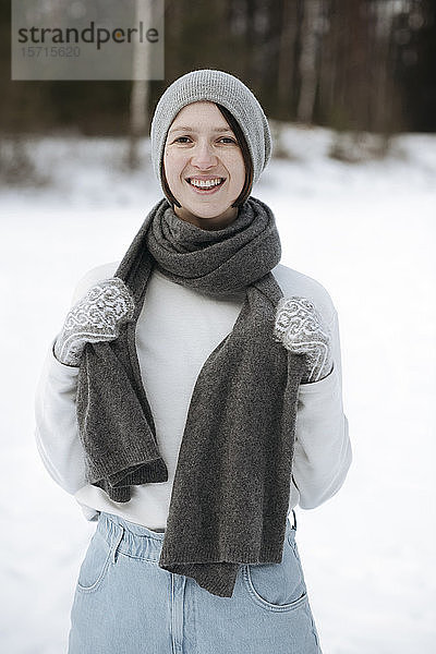 Porträt einer glücklichen Frau auf einem Schneefeld stehend