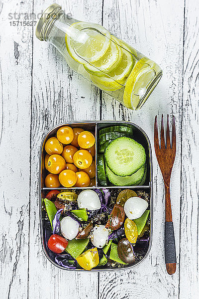 Limonadenflasche und Lunchbox mit Gurkenscheiben  Winterkirschen und Quinoa-Salat (Quinoa  Kirschtomate  Rotkohl  Zuckerschoten und Mozzarellakugeln)