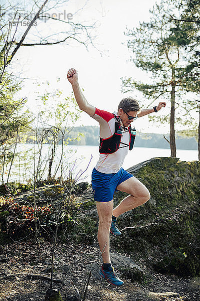 Mann rennt am Seeufer und springt über ein Hindernis  Forstsee  Kärnten  Österreich