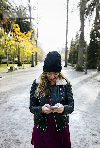 Hübsche blonde Frau benutzt ihr Smartphone in einem Park