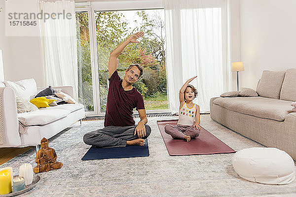 Vater und Tochter machen zu Hause gemeinsam Yoga