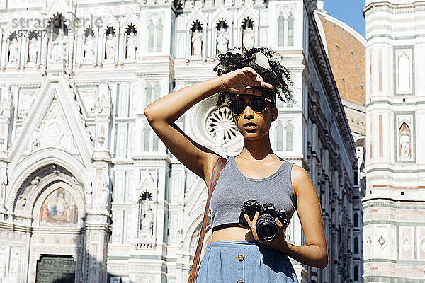Porträt einer jungen Frau mit Kamera vor der Kathedrale stehend  Florenz  Italien