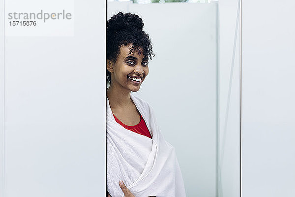Porträt einer glücklichen  in ein Handtuch gewickelten jungen Frau